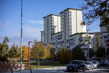 Torino, İtalya - 08 Kasım 2021: Via Valprato ve Parco Aurelio Peccei yakınlarındaki modern apartmanlar, park halindeki arabalar ve sonbahar yeşillikleri görünür