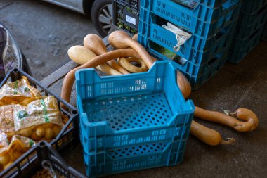 Torino, İtalya - 08 Kasım 2021: Tromboncino kabağı ve şehir sokaklarında mavi ve siyah plastik kasaların yanında patates çuvalları