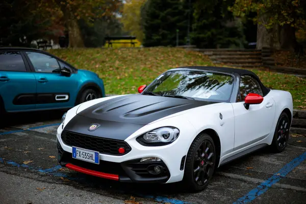 Torino, İtalya - 08 Kasım 2021: Siyah kapüşonlu ve kırmızı aksanlı üstü açık beyaz Abarth 124 Spider bir park yerine park etti