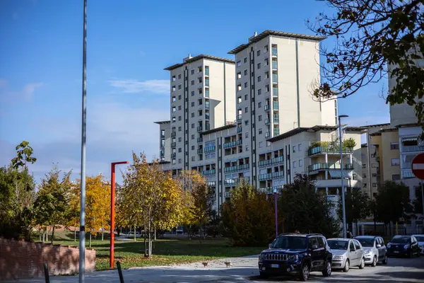 Torino, İtalya - 08 Kasım 2021: Via Valprato ve Parco Aurelio Peccei yakınlarındaki modern apartmanlar, park halindeki arabalar ve sonbahar yeşillikleri görünür