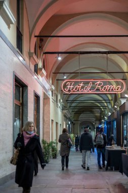 Torino, İtalya - 09 Kasım 2021: İnsanlarla dolu kemerli bir geçitte ışıklandırılmış neon tabela 