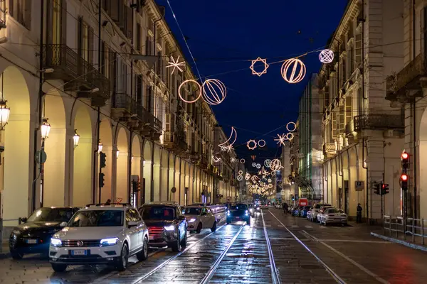 Torino, İtalya - 09 Kasım 2021: Noel aydınlatmaları, araba trafiği, tramvay rayları ve ıslak kaldırım taşlarıyla Via Po 'nun gece görüşü.