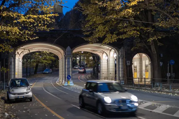 Torino, İtalya - 09 Kasım 2021: Giardini Reali di Torino 'nun üzerine alacakaranlık çöktüğünde, arabalar, sonbahar ağaçları tarafından çerçevelenmiş Viale' nin yumuşak, zarif kemerlerinde ilerliyorlar..