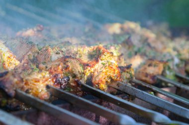 Yakın plan, kar kaplı ahşap bir çatının kenarından sarkan keskin, şeffaf buz saçakları, karla kaplı dalların bulanık bir görüntüsü ve arka planda birkaç kahverengi yaprak gösteriyor..