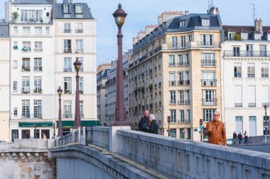 Paris, Fransa - 9 Kasım 2011: İnsanlar Paris 'teki Pont de la Tournelle kaldırımında Seine Nehri' ni bulutlu bir gökyüzünün altında kaplayan binalarla yürüyorlar