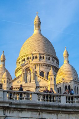 Paris, Fransa - 9 Kasım 2011: Montmartre tepesindeki Sacre-Ceour Bazilikası, Romano-Bizans mimari harikası. Ziyaretçiler çimlerde ve merdivenlerde dinleniyor, bu ikonik simgenin güneşli manzarasının tadını çıkarıyorlar..