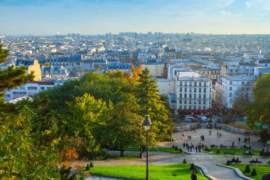 Paris, Fransa - 9 Kasım 2011: Parkın Montmartre tepesinden ve Paris panoramasından görüntü. İnsanlar sıcak bir sonbahar akşamı parkta yürüyorlar..