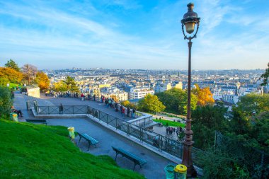Paris, Fransa - 9 Kasım 2011: Montmartre 'den panoramik manzara. Ön planda, insanlar korkulukların yanında durup Paris siluetinin keyfini çıkarıyorlar. Tarihi binalar ve canlı şehir manzarası