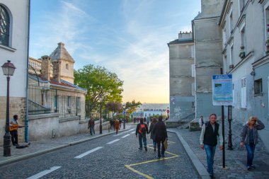 Paris, Fransa - 9 Kasım 2011: Montmartre Sacre-Ceour Bazilikası yakınlarında. Bir müzisyen ağaçlarla kaplı bir kaldırım taşı caddesi boyunca gitar çalar. Ziyaretçiler tarihi bölgede geziniyor.