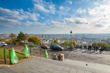 Paris, Fransa - 9 Kasım 2011: Montmartre 'den Paris manzarası. Merdivenler ön plandan asfalt bir alana iniyor, ağaçlarla çevrili. İnsanlar metal bir çitin yanında durup manzaranın tadını çıkarıyor..