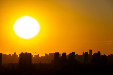 Anavatan Anıtı 'nın ve Ukrayna bayrağının belirgin bir şekilde dalgalandığı uzun bir bayrak direğinin yer aldığı Kyiv silueti üzerinde dramatik bir günbatımı..
