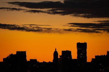 Puslu bir günbatımı Kyiv siluetini sıcak, altın bir ışıltıyla yıkar. Çeşitli binaları siluete boğar. Buna Kyiv Pechersk Lavra 'nın çan kulesi de dahil..