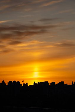 Anavatan Anıtı 'nın ve Ukrayna bayrağının belirgin bir şekilde dalgalandığı uzun bir bayrak direğinin yer aldığı Kyiv silueti üzerinde dramatik bir günbatımı..