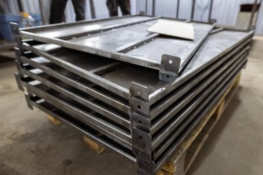 Bir atölye veya fabrika ayarı ahşap palet üzerine bağlı yeni üretilmiş metal çerçeve yığını.