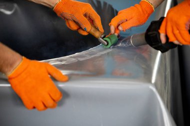Parçalanmış bir dizel kamyon motoru işlek bir tamirhanede ya da depoda ahşap desteklerin üzerinde yatıyor ve arka planda eğimli bir kamyon taksisi görünüyor.