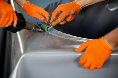 Parçalanmış bir dizel kamyon motoru işlek bir tamirhanede ya da depoda ahşap desteklerin üzerinde yatıyor ve arka planda eğimli bir kamyon taksisi görünüyor.