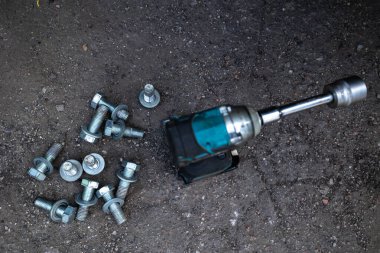 Parçalanmış bir dizel kamyon motoru işlek bir tamirhanede ya da depoda ahşap desteklerin üzerinde yatıyor ve arka planda eğimli bir kamyon taksisi görünüyor.