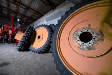 Parçalanmış bir dizel kamyon motoru işlek bir tamirhanede ya da depoda ahşap desteklerin üzerinde yatıyor ve arka planda eğimli bir kamyon taksisi görünüyor.