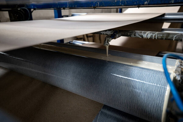 A disassembled diesel truck engine lies on wooden supports in a busy repair shop or warehouse, with a tilted truck cab visible in the background