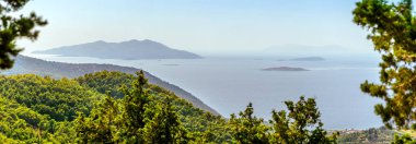 Rodos 'un batı kıyısından geniş, puslu bir manzara Ege Denizi ve adalara bakar: Halki, Theodoros, Tragousa, Alimia, Marki ve Tilos..