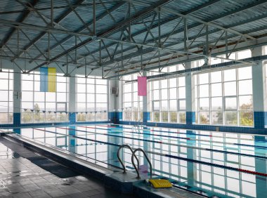 Beş şeritli havuz, temiz su, şerit işaretleri ve giriş için merdiven. İçinin yansıdığı pürüzsüz bir su yüzeyi. Büyük pencereler doğal ışık sağlar.