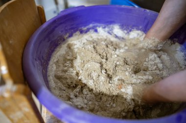 El yapımı ekmek hazırlama işlemi sırasında büyük plastik bir kabın içinde hamur yoğuran eller. Hamur yapış yapış ve yapış, aktif karışımı gösteriyor..