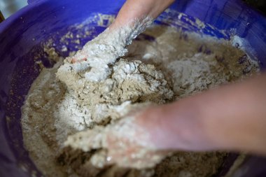El yapımı ekmek hazırlama işlemi sırasında büyük plastik bir kabın içinde hamur yoğuran eller. Hamur yapış yapış ve yapış, aktif karışımı gösteriyor..