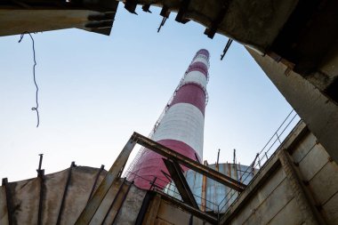 Yüksek kapasiteli bir termik santralde devasa bir gaz egzoz sistemi. Yüksek kırmızı-beyaz bacalar 150 metreyi aşarak emisyon yönetimi ve endüstriyel hava dolaşımını kolaylaştırıyor..