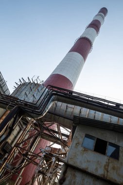 Yüksek kapasiteli bir termik santralde devasa bir gaz egzoz sistemi. Yüksek kırmızı-beyaz bacalar 150 metreyi aşarak emisyon yönetimi ve endüstriyel hava dolaşımını kolaylaştırıyor..