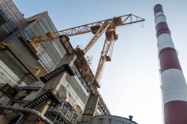 Yüksek kapasiteli bir termik santralde devasa bir gaz egzoz sistemi. Yüksek kırmızı-beyaz bacalar 150 metreyi aşarak emisyon yönetimi ve endüstriyel hava dolaşımını kolaylaştırıyor..