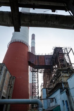 Yüksek kapasiteli bir termik santralde devasa bir gaz egzoz sistemi. Yüksek kırmızı-beyaz bacalar 150 metreyi aşarak emisyon yönetimi ve endüstriyel hava dolaşımını kolaylaştırıyor..