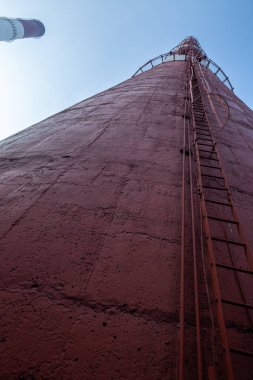 Yüksek kapasiteli bir termik santralde devasa bir gaz egzoz sistemi. Yüksek kırmızı-beyaz bacalar 150 metreyi aşarak emisyon yönetimi ve endüstriyel hava dolaşımını kolaylaştırıyor..