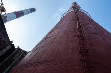 Yüksek kapasiteli bir termik santralde devasa bir gaz egzoz sistemi. Yüksek kırmızı-beyaz bacalar 150 metreyi aşarak emisyon yönetimi ve endüstriyel hava dolaşımını kolaylaştırıyor..