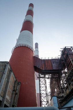 Yüksek kapasiteli bir termik santralde devasa bir gaz egzoz sistemi. Yüksek kırmızı-beyaz bacalar 150 metreyi aşarak emisyon yönetimi ve endüstriyel hava dolaşımını kolaylaştırıyor..