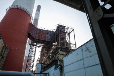 Yüksek kapasiteli bir termik santralde devasa bir gaz egzoz sistemi. Yüksek kırmızı-beyaz bacalar 150 metreyi aşarak emisyon yönetimi ve endüstriyel hava dolaşımını kolaylaştırıyor..