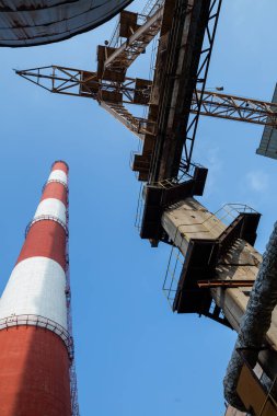 Yüksek kapasiteli bir termik santralde devasa bir gaz egzoz sistemi. Yüksek kırmızı-beyaz bacalar 150 metreyi aşarak emisyon yönetimi ve endüstriyel hava dolaşımını kolaylaştırıyor..