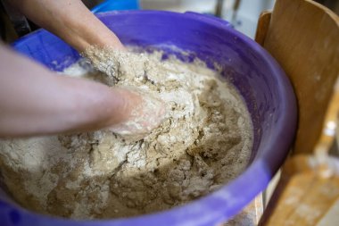 El yapımı ekmek hazırlama işlemi sırasında büyük plastik bir kabın içinde hamur yoğuran eller. Hamur yapış yapış ve yapış, aktif karışımı gösteriyor..