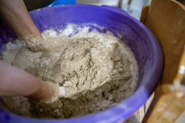El yapımı ekmek hazırlama işlemi sırasında büyük plastik bir kabın içinde hamur yoğuran eller. Hamur yapış yapış ve yapış, aktif karışımı gösteriyor..