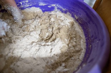El yapımı ekmek hazırlama işlemi sırasında büyük plastik bir kabın içinde hamur yoğuran eller. Hamur yapış yapış ve yapış, aktif karışımı gösteriyor..