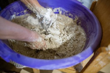 El yapımı ekmek hazırlama işlemi sırasında büyük plastik bir kabın içinde hamur yoğuran eller. Hamur yapış yapış ve yapış, aktif karışımı gösteriyor..
