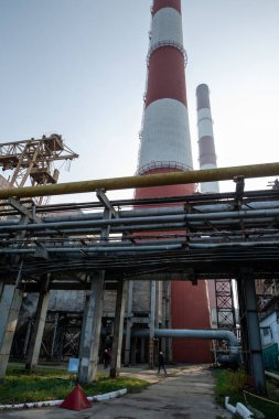 Yüksek kapasiteli bir termik santralde devasa bir gaz egzoz sistemi. Yüksek kırmızı-beyaz bacalar 150 metreyi aşarak emisyon yönetimi ve endüstriyel hava dolaşımını kolaylaştırıyor..