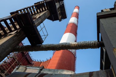Yüksek kapasiteli bir termik santralde devasa bir gaz egzoz sistemi. Yüksek kırmızı-beyaz bacalar 150 metreyi aşarak emisyon yönetimi ve endüstriyel hava dolaşımını kolaylaştırıyor..