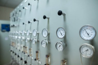 Sanayi sisteminde sıvı veya gaz basıncını düzenlemek için kullanılan çoklu basınç göstergelerine ve ayarlama düğmelerine sahip kontrol paneli. Ölçüler çeşitli basınç seviyelerini gösterir