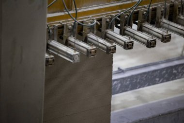 Havalandırılmış beton bloklar, AAC blokları (Otoklavize havalandırmalı beton), Fly ash veya Grey Cement Fly Ash Bricks endüstriyel üretimi. Makine, büyük iş parçalarını çelik tellerle keser..