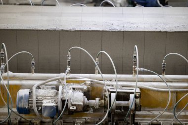 Havalandırılmış beton bloklar, AAC blokları (Otoklavize havalandırmalı beton), Fly ash veya Grey Cement Fly Ash Bricks endüstriyel üretimi. Makine, büyük iş parçalarını çelik tellerle keser..