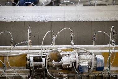 Havalandırılmış beton bloklar, AAC blokları (Otoklavize havalandırmalı beton), Fly ash veya Grey Cement Fly Ash Bricks endüstriyel üretimi. Makine, büyük iş parçalarını çelik tellerle keser..