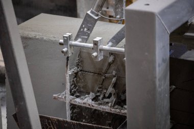 Havalandırılmış beton bloklar, AAC blokları (Otoklavize havalandırmalı beton), Fly ash veya Grey Cement Fly Ash Bricks endüstriyel üretimi. Makine, büyük iş parçalarını çelik tellerle keser..