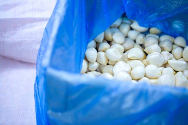 İnce buz kaplamalı, dondurulmuş sarımsak soğanlarının yakın çekimi. Süpermarketlerde raf ömrünün uzatılması ve bozulabilir hasat kalitesinin korunması için perakende paketlemeye hazırlar..