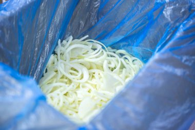 Donmuş soğan halkaları ve ince buz kaplamalı yarım halkalar yakın çekim. Süpermarketlerde raf ömrünün uzatılması ve bozulabilir hasat kalitesinin korunması için perakende paketlemeye hazırlar..
