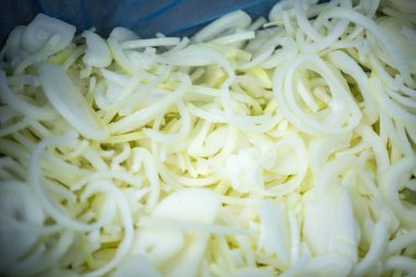 Donmuş soğan halkaları ve ince buz kaplamalı yarım halkalar yakın çekim. Süpermarketlerde raf ömrünün uzatılması ve bozulabilir hasat kalitesinin korunması için perakende paketlemeye hazırlar..